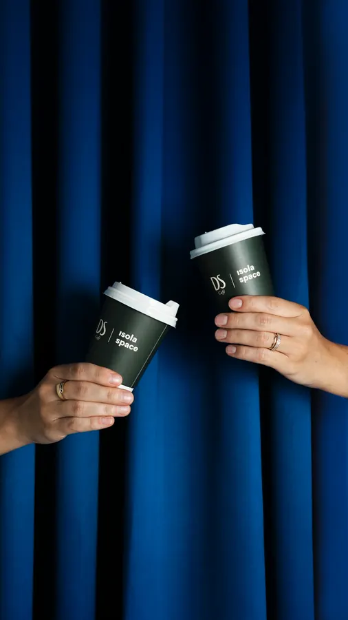 Two DS cups clinking in front of a blue curtain
